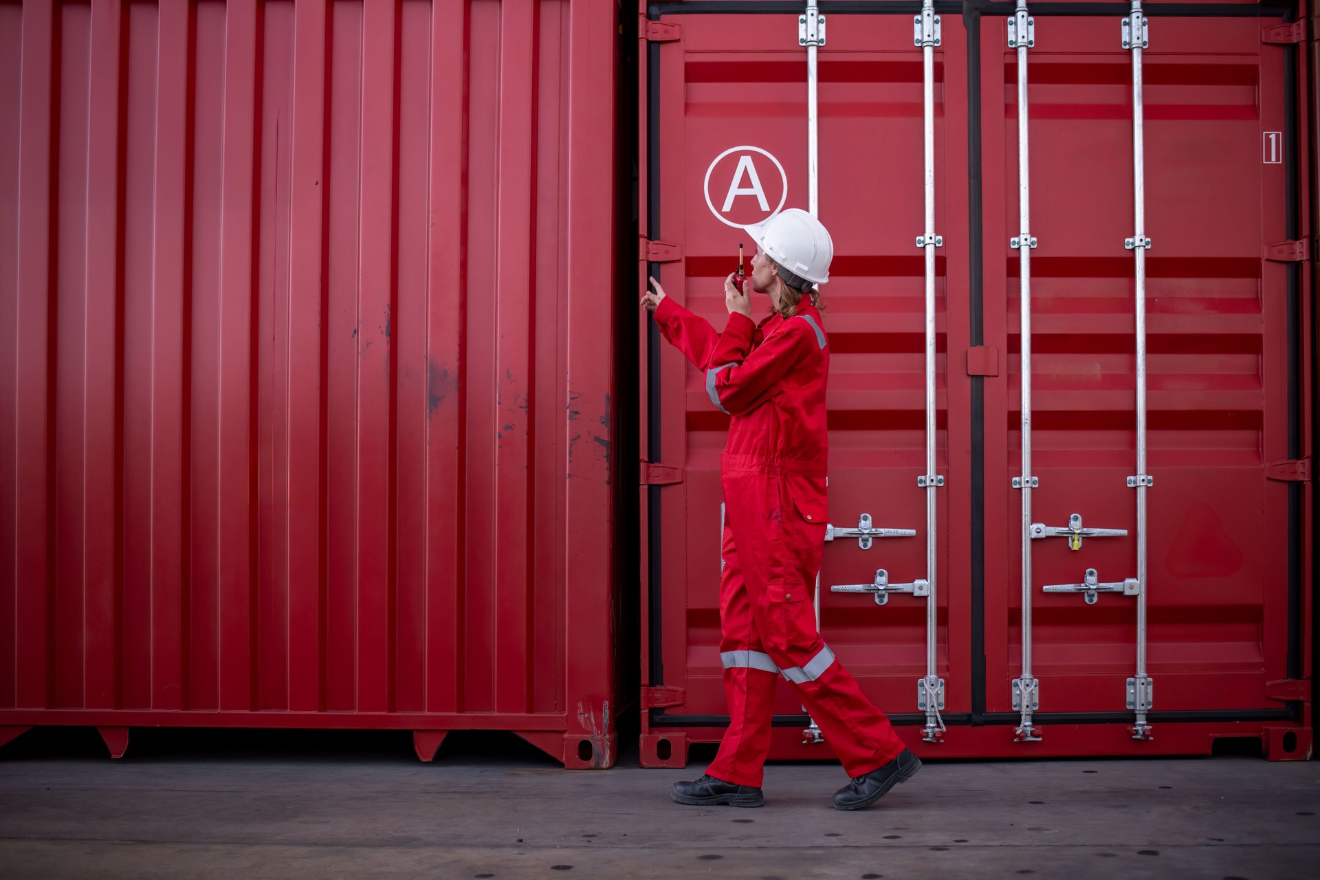 Engineer or dockworker working in the construction container dock yard checking and inspection containers data on program environment is container shipping Logistics business concept.