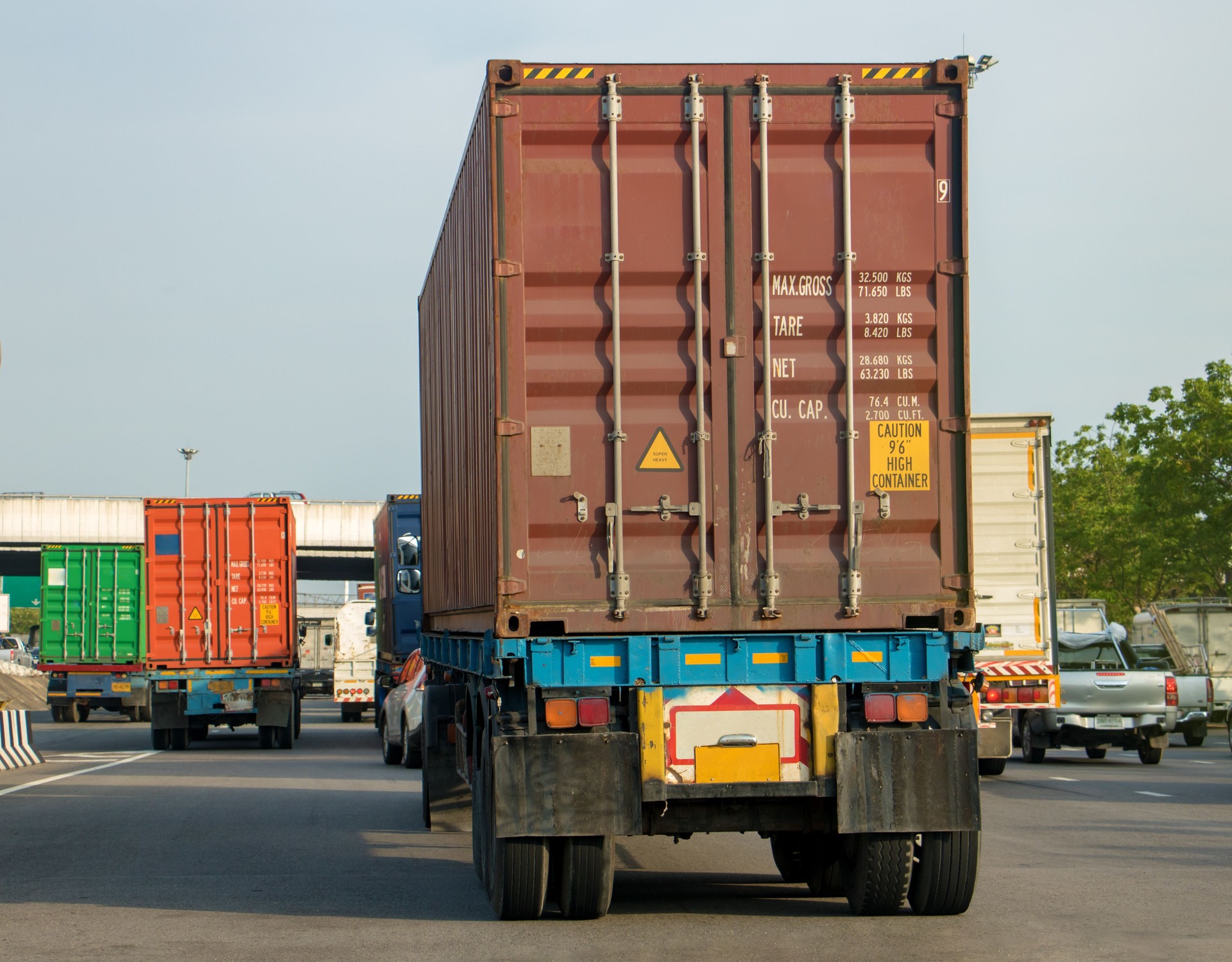 Container transport by truck on the highway. Trucks transporting color containers by road, rear view.