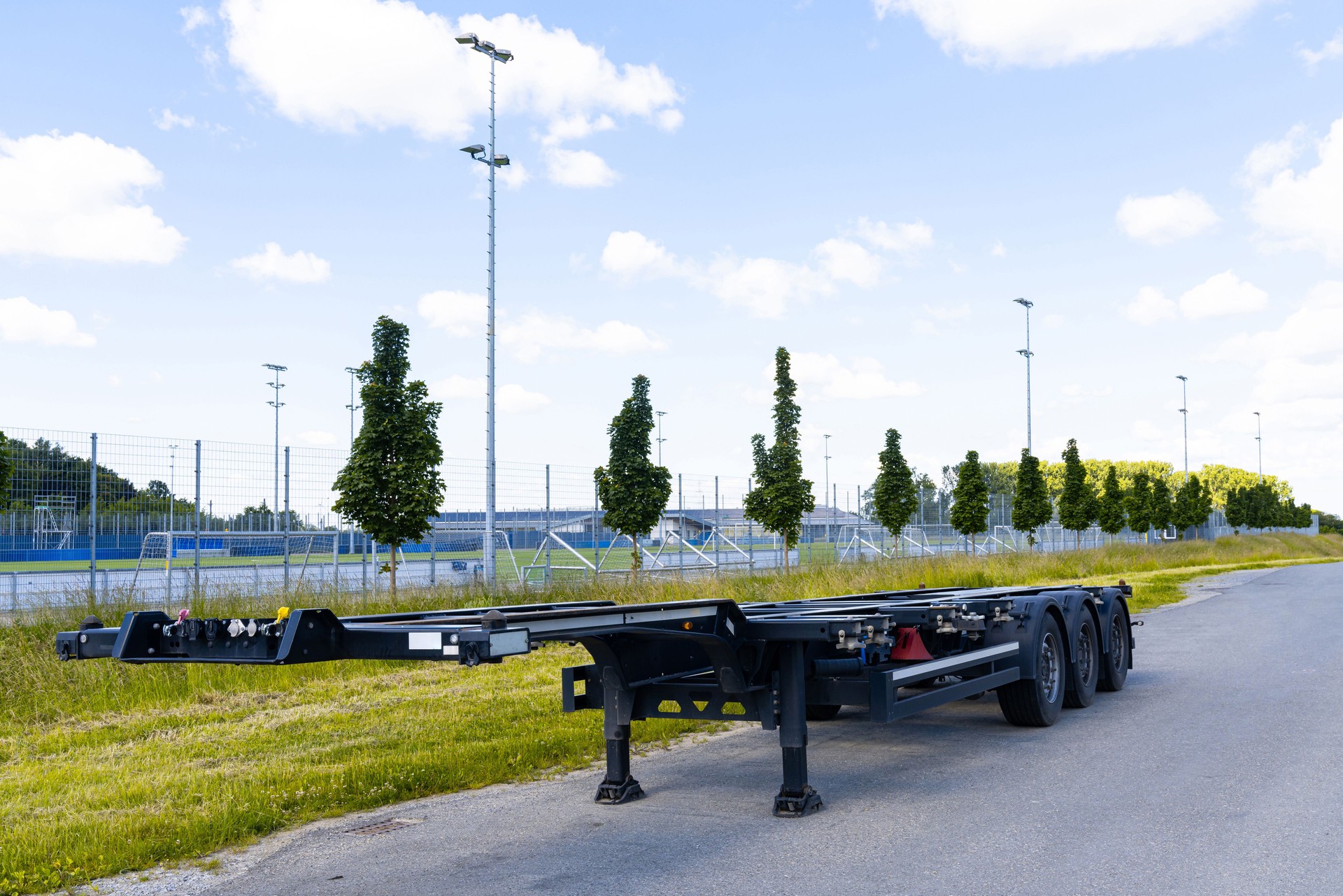 A lone trailer parked beside a lush green field .