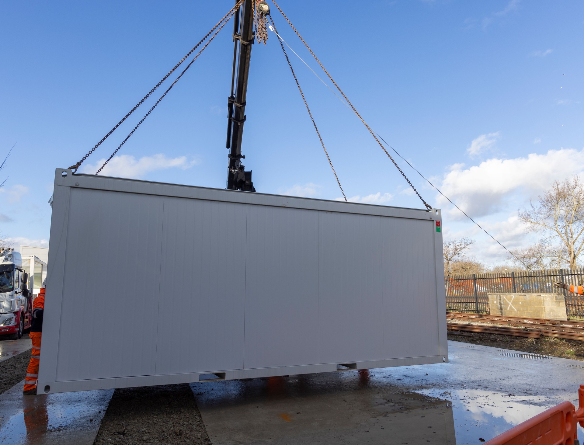 Construction workers in High Visibility clothes Assembling a Shipping Container style Modular Building from a Crane 3